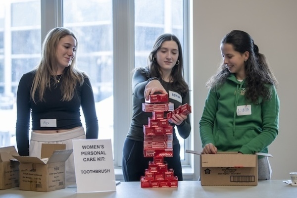 Three young women stacking boxes of toothpaste to hand out.